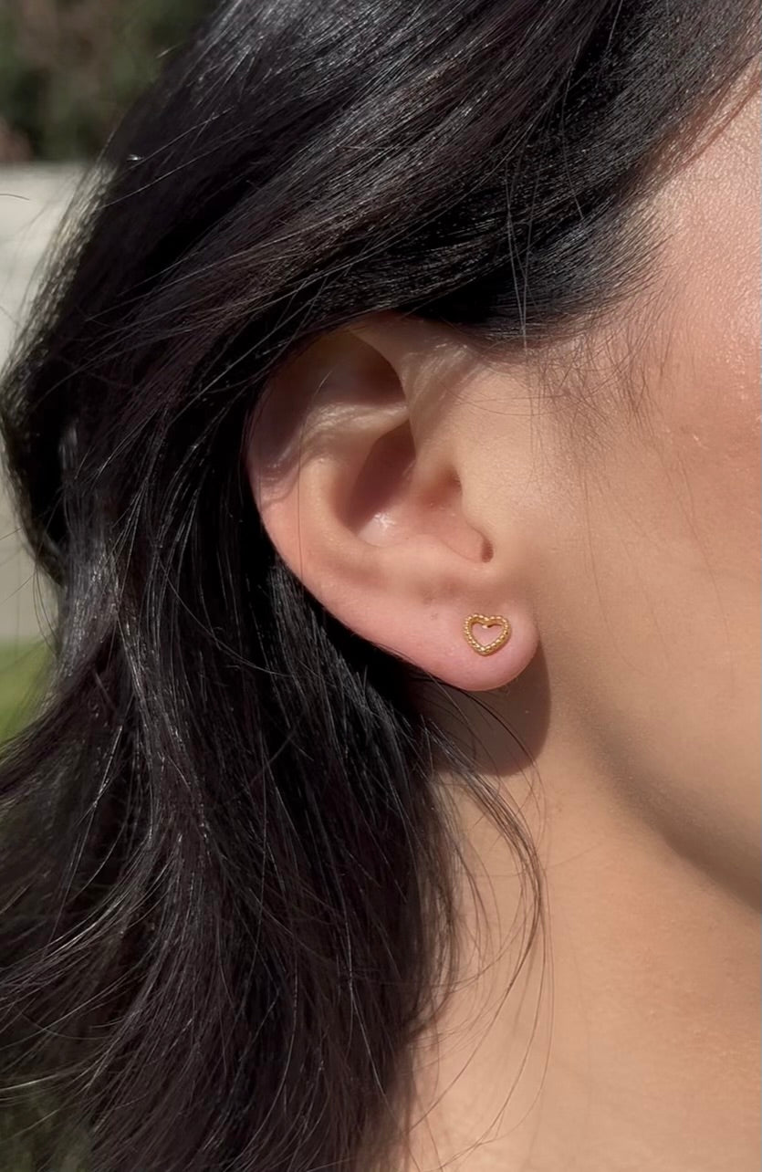 Woman wearing minimalist gold heart earrings close-up