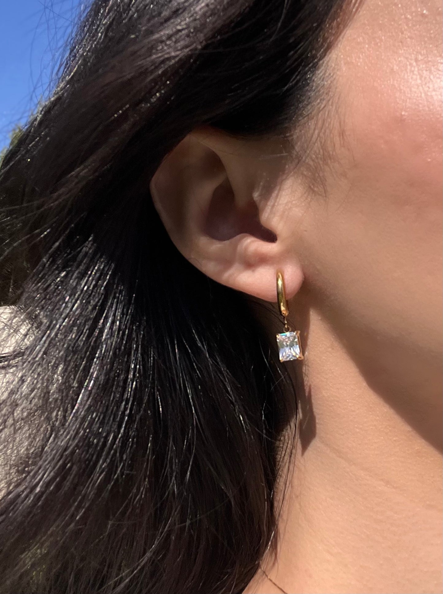 Woman wearing gold hoop drop earrings in sunlight