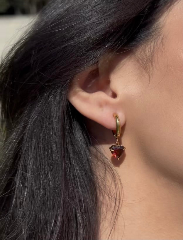 Woman wearing red heart-shaped drop earrings