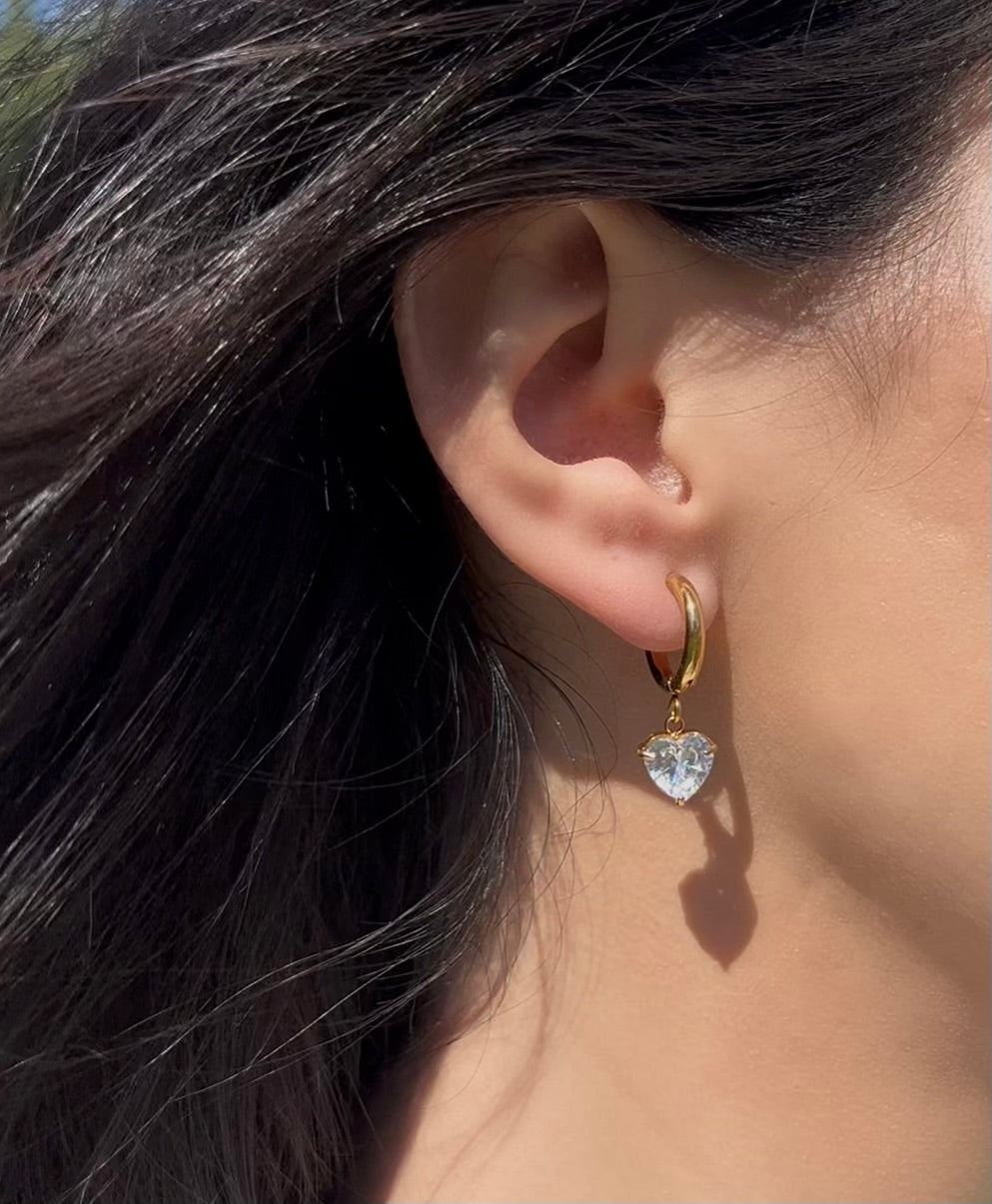 Woman wearing gold heart drop earrings outdoors