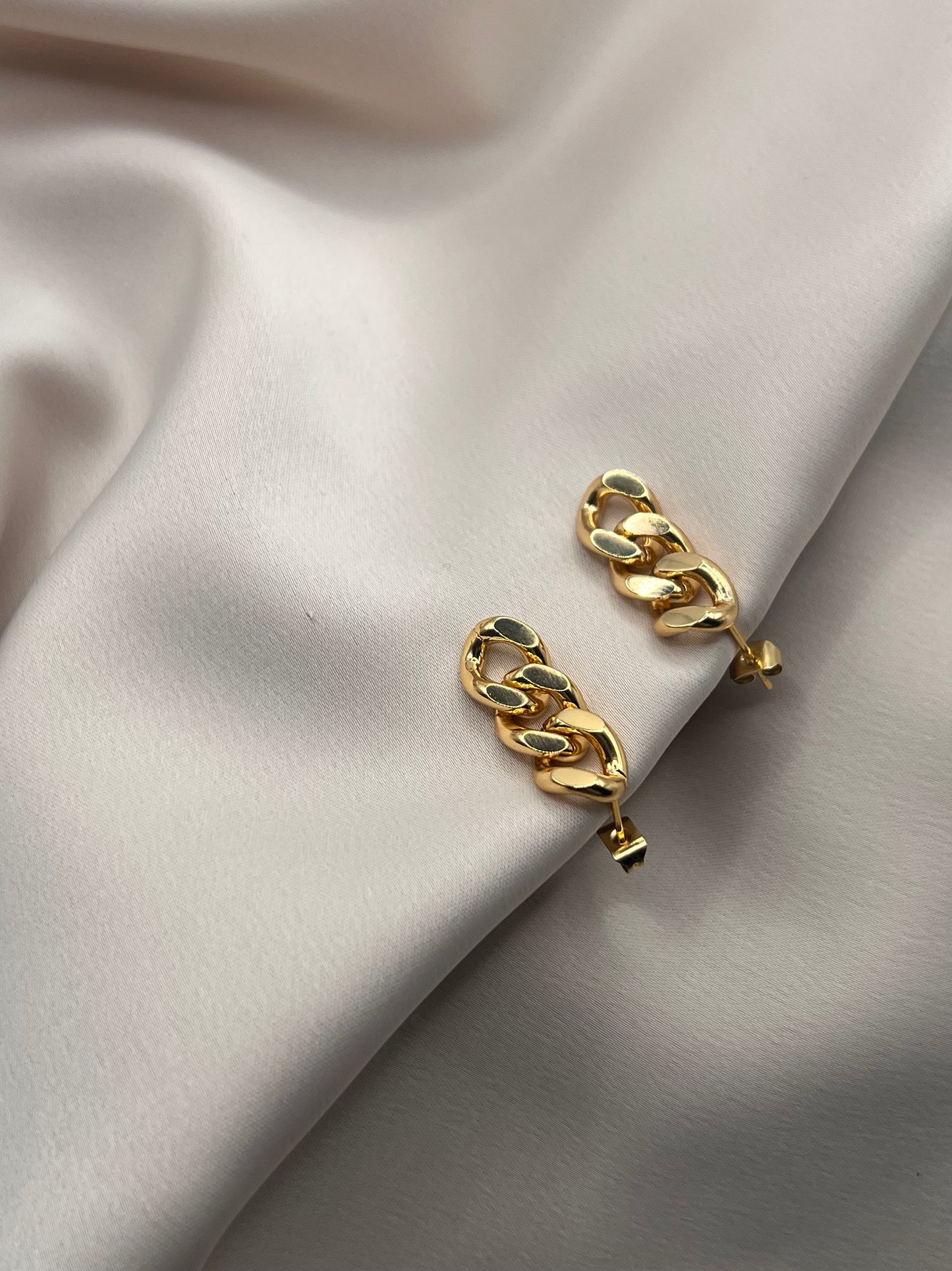 Gold statement earrings on satin background