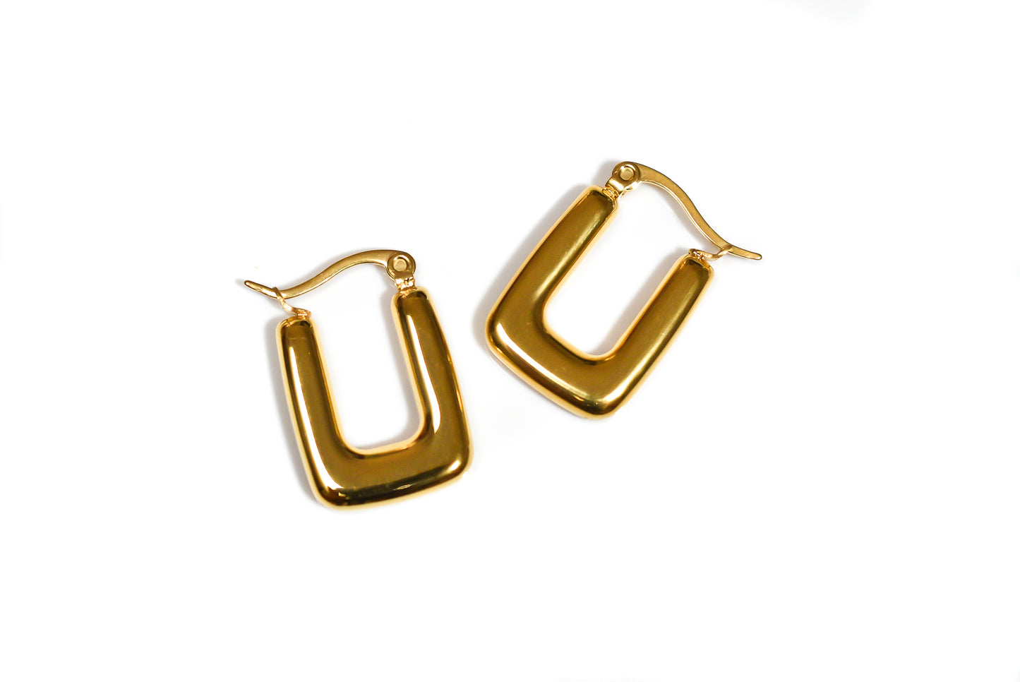 Bold gold hoop earrings with modern design photographed flat lay