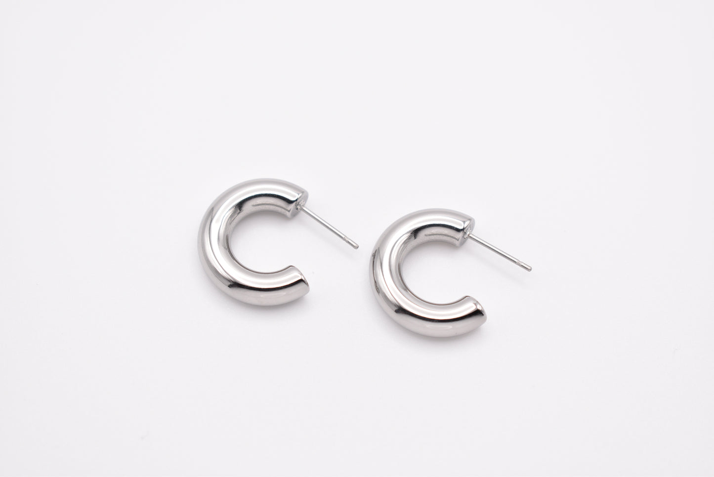 Pair of silver stainless steel hoop earrings on white background