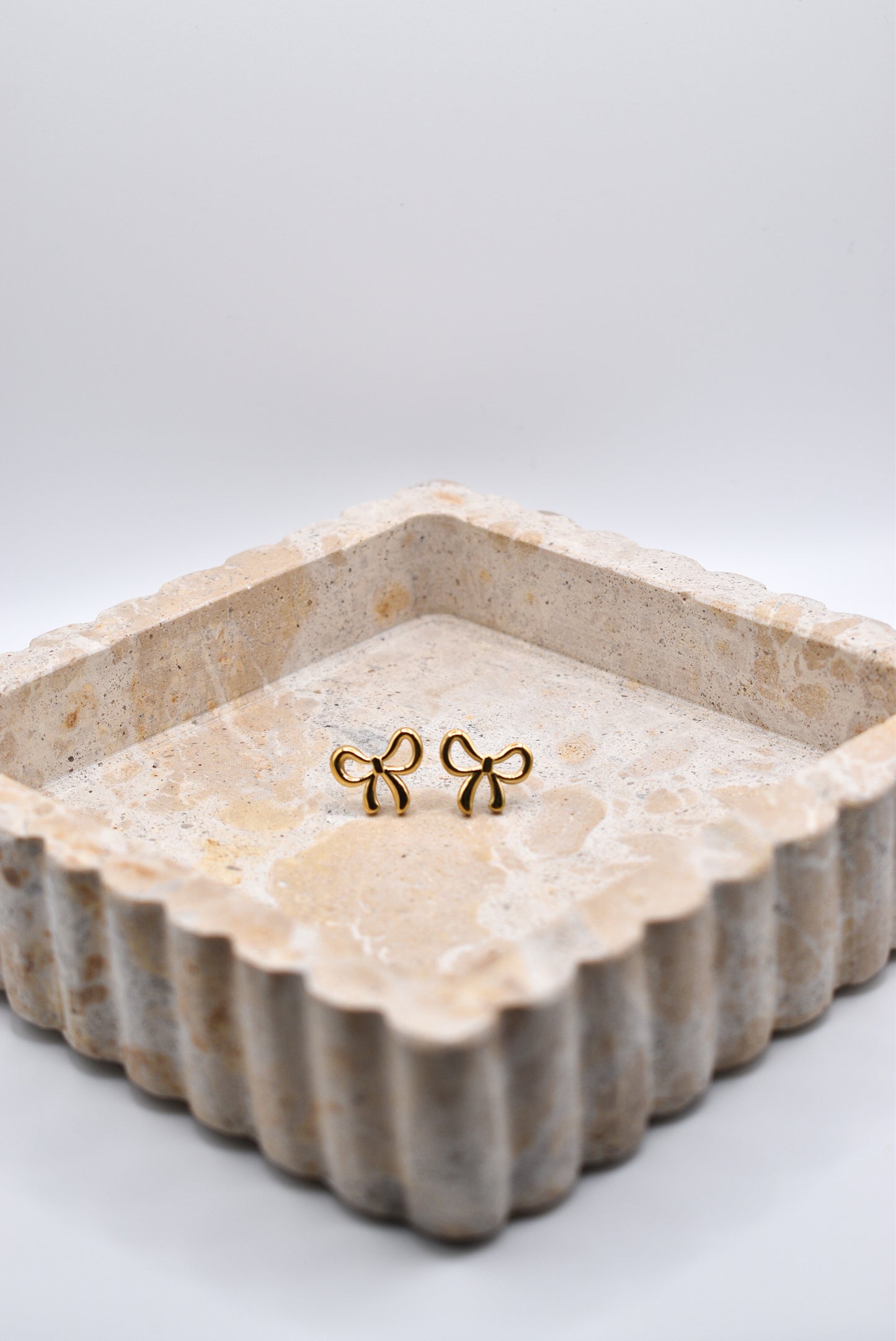 Gold bow earrings styled in jewelry dish