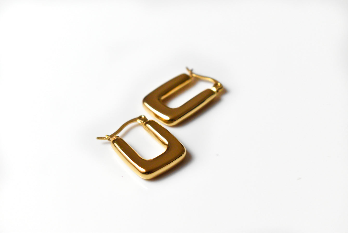 Chunky gold hoop earrings made from titanium on white background