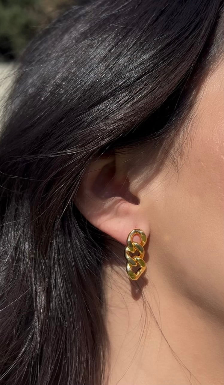Woman wearing luminous chunky gold earrings outdoors
