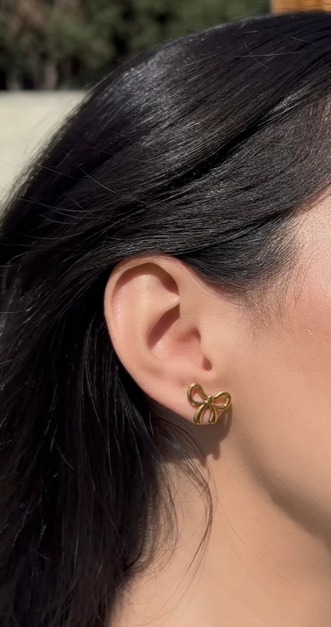 Close-up of woman wearing gold bow earrings