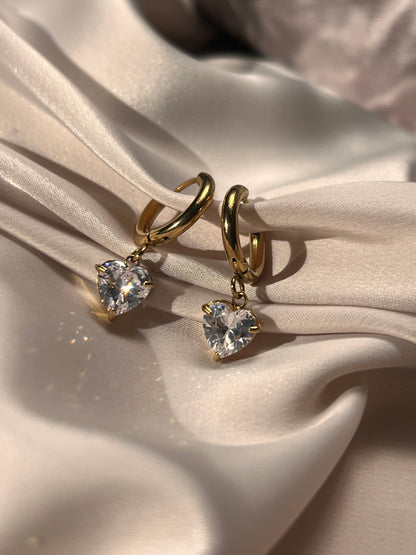 Gold heart hoop earrings styled on satin fabric

