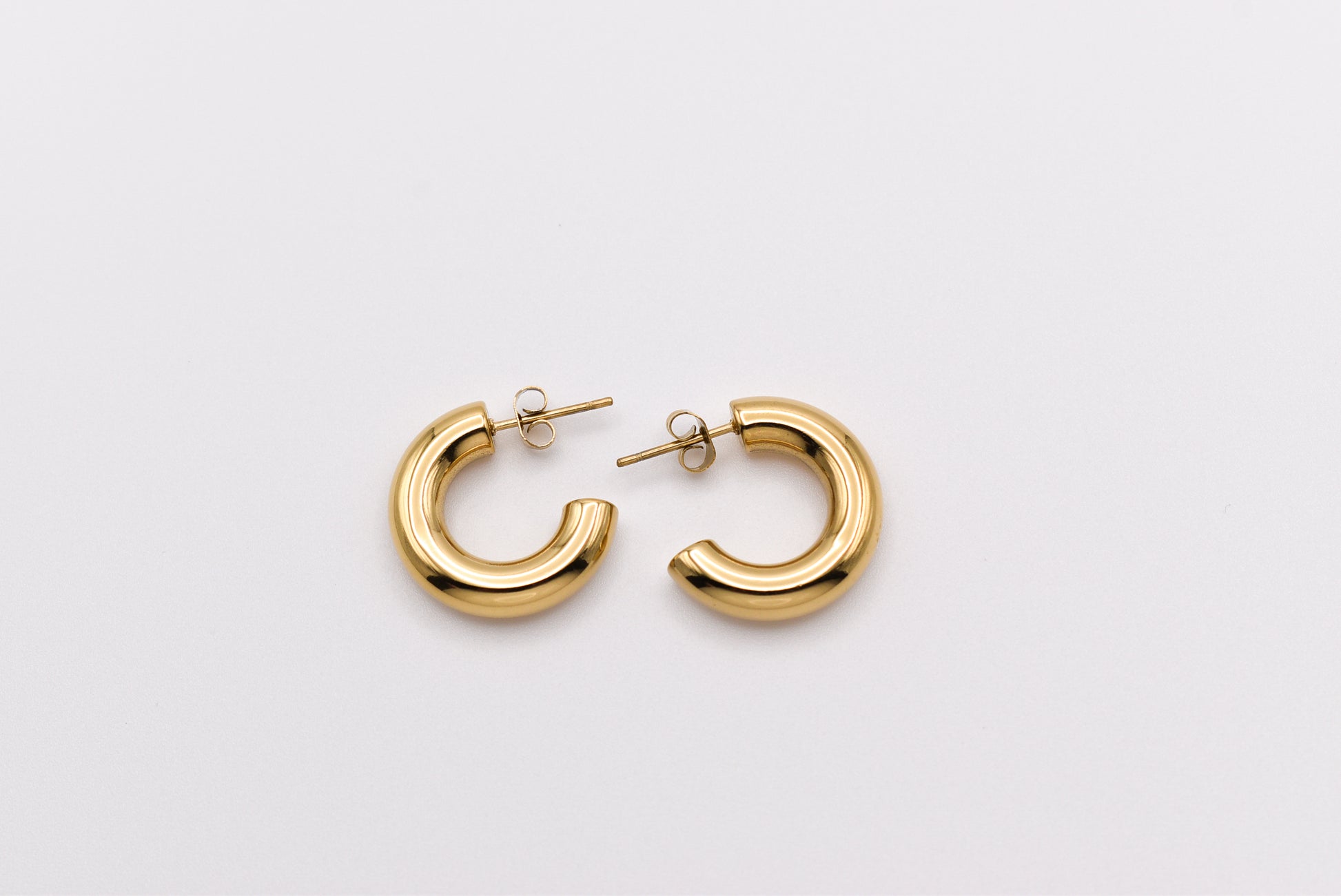 Chunky gold hoop earrings on white background