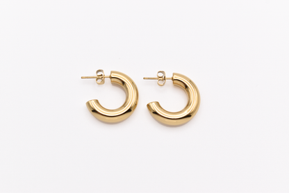 Chunky gold hoop earrings on white background