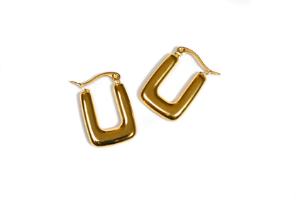 Bold gold hoop earrings with modern design photographed flat lay