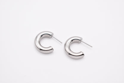 Pair of silver stainless steel hoop earrings on white background