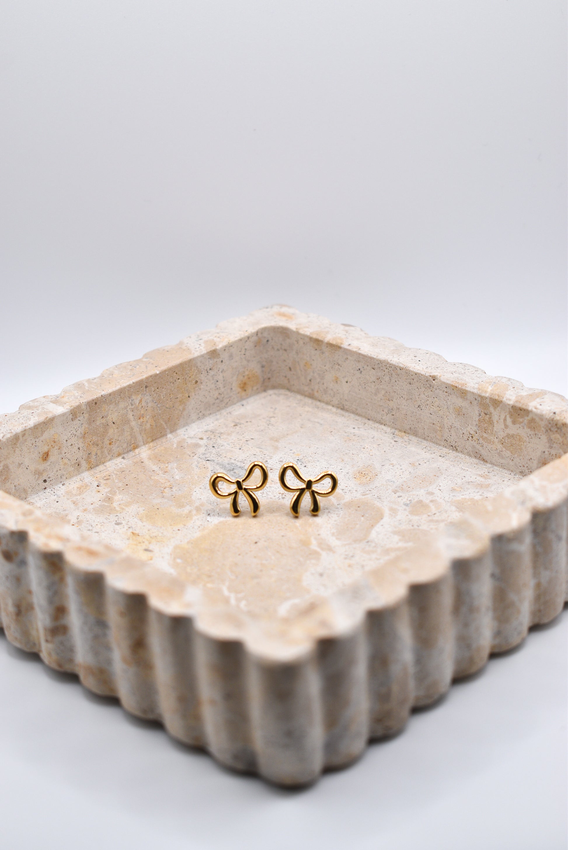 Gold bow earrings styled in jewelry dish