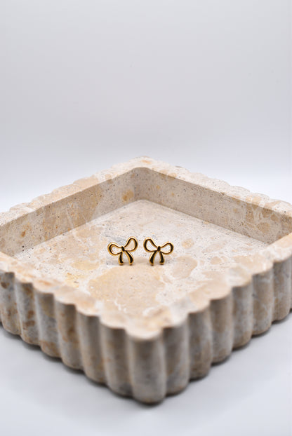 Gold bow earrings styled in jewelry dish